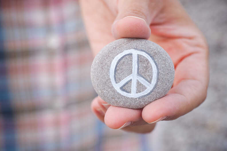 Mann hält Stein mit Peace-Symbol in der Hand