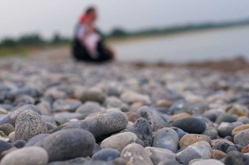 Frau mit Kind an einem Steinstrand